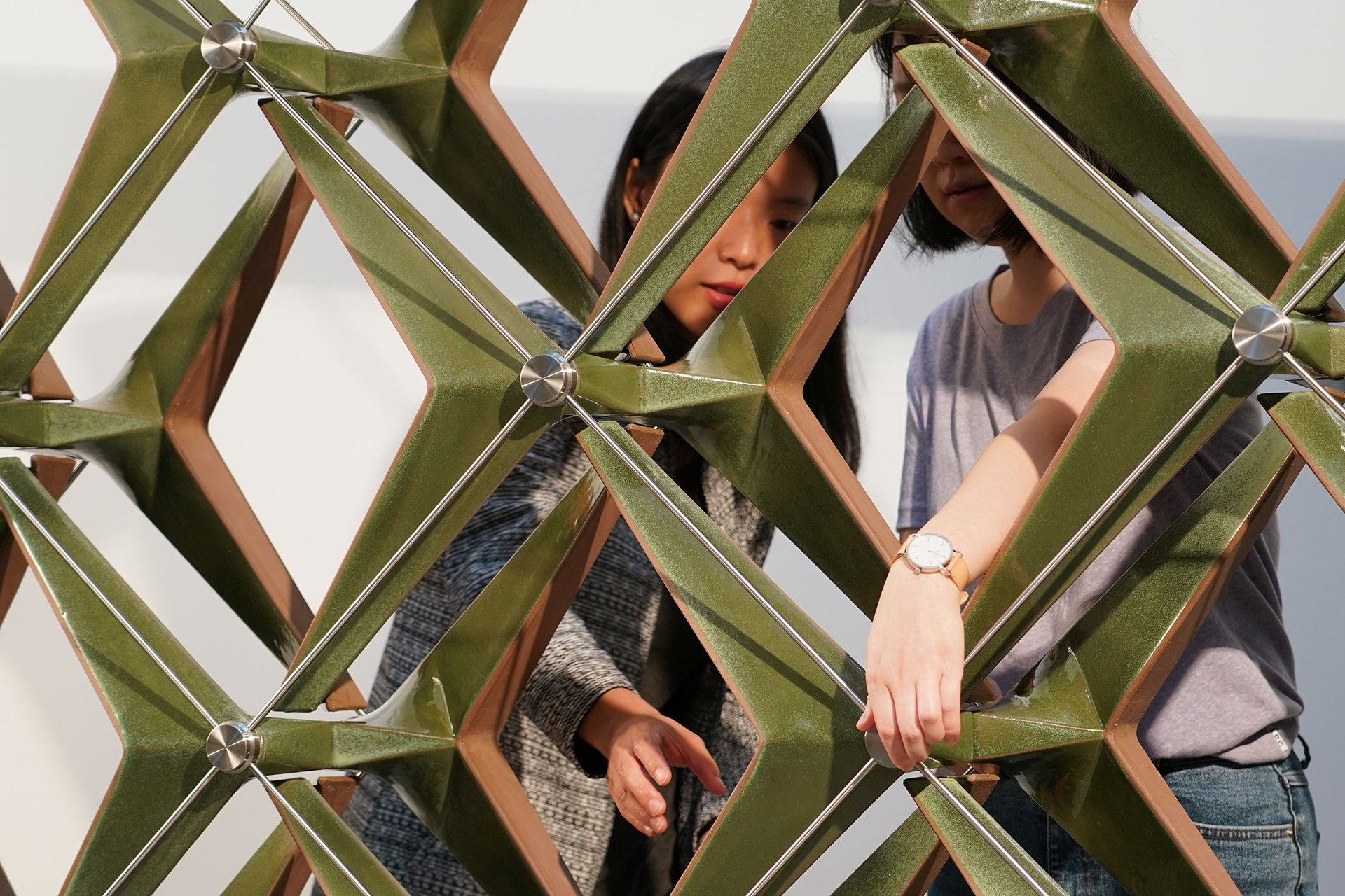 Two women constructing large geometric structure