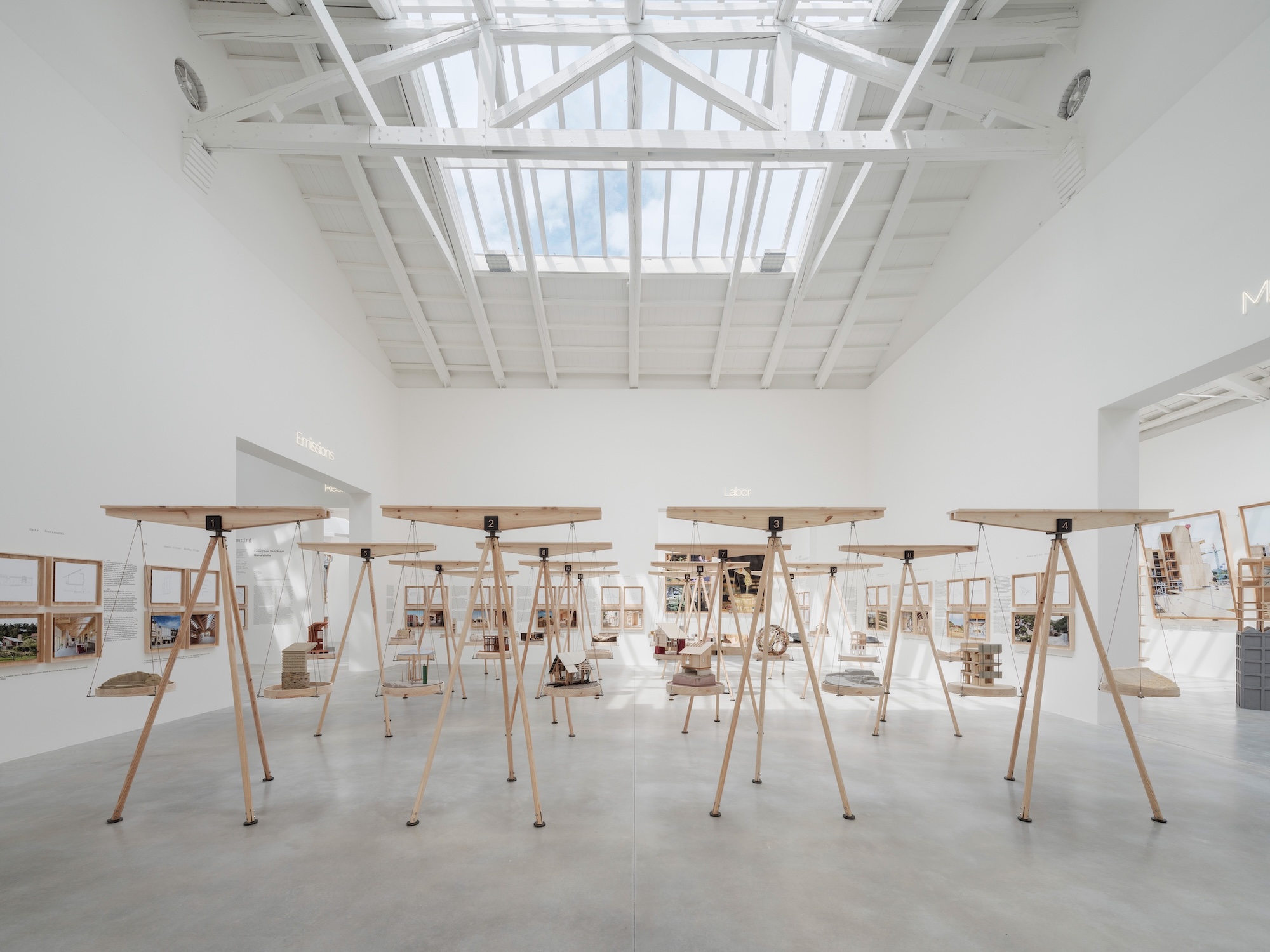 Interior of a large white room with wooden sculptural stands arranged throughout the space.