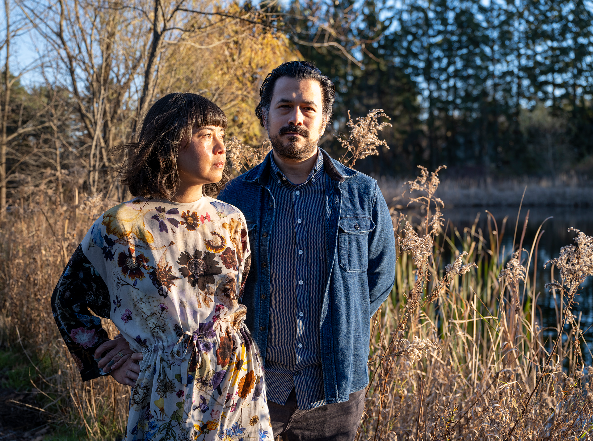 And man and woman standing in a wooded field at sunset