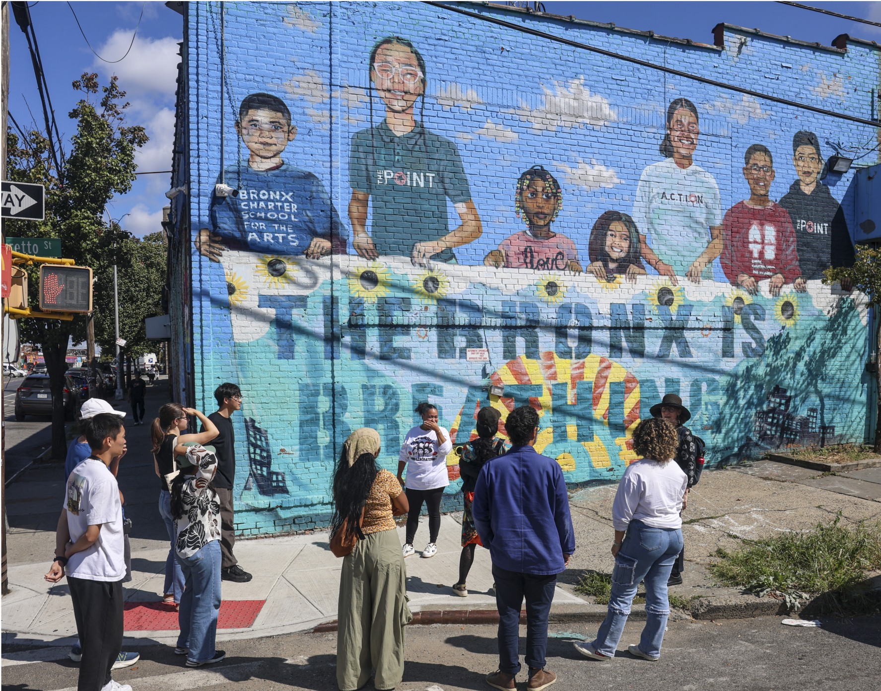 People on an urban street corner observing a mural