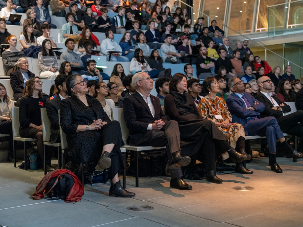 Crowd gathered in a raked lecture hall.