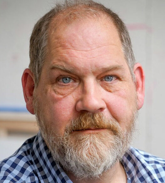 Man with a beard wearing a blue and white checkered shirt.