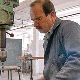 portrait of a man wearing a blue jacket using a drill press