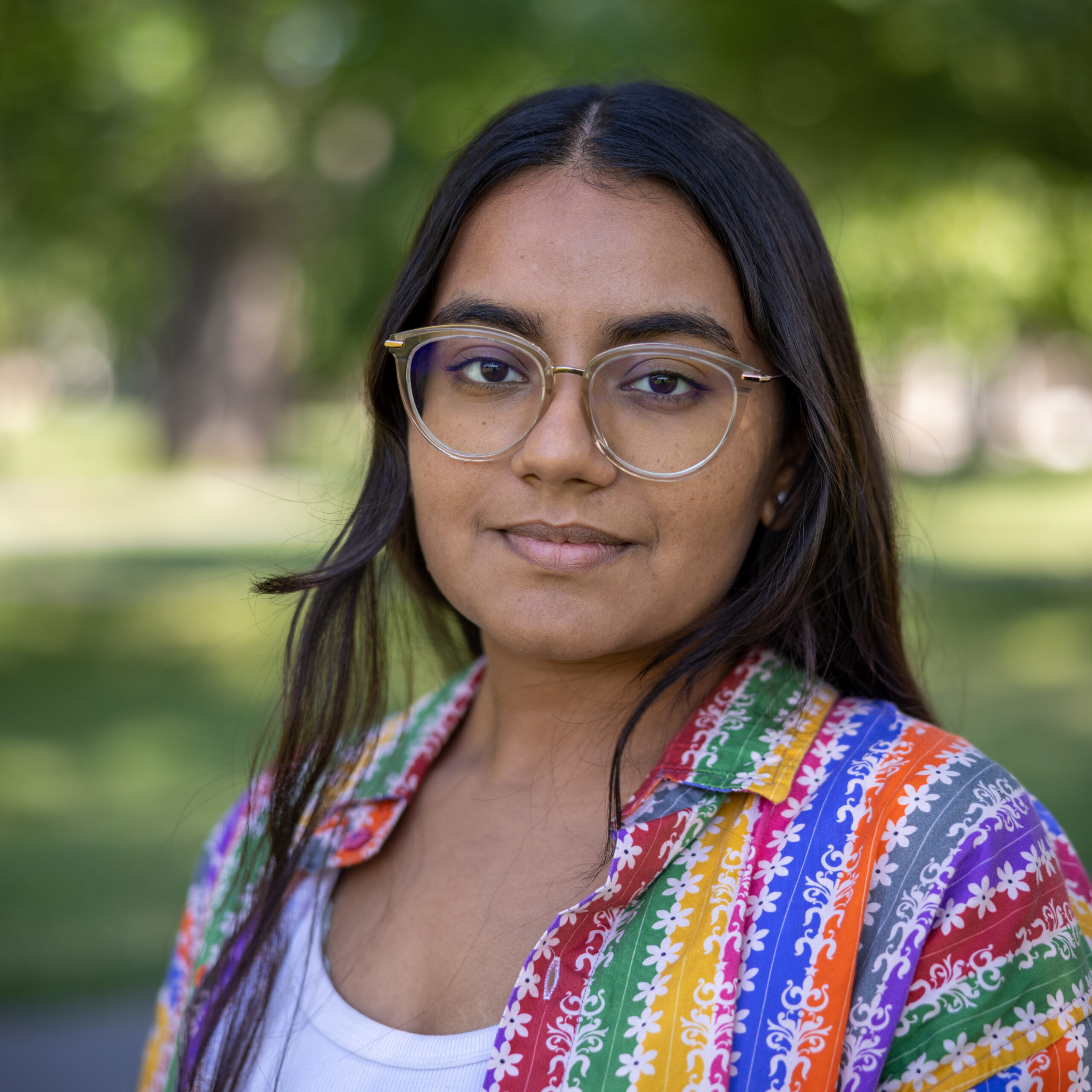 Person wearing glasses and colorful striped sweater over white undershirt