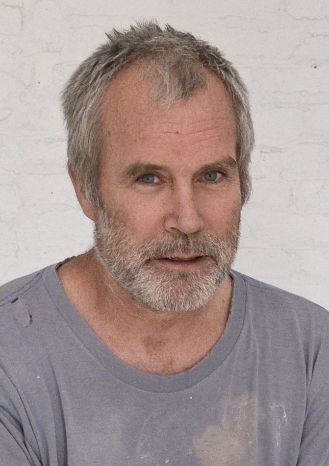 Man with grey hair wearing a grey t-shirt.