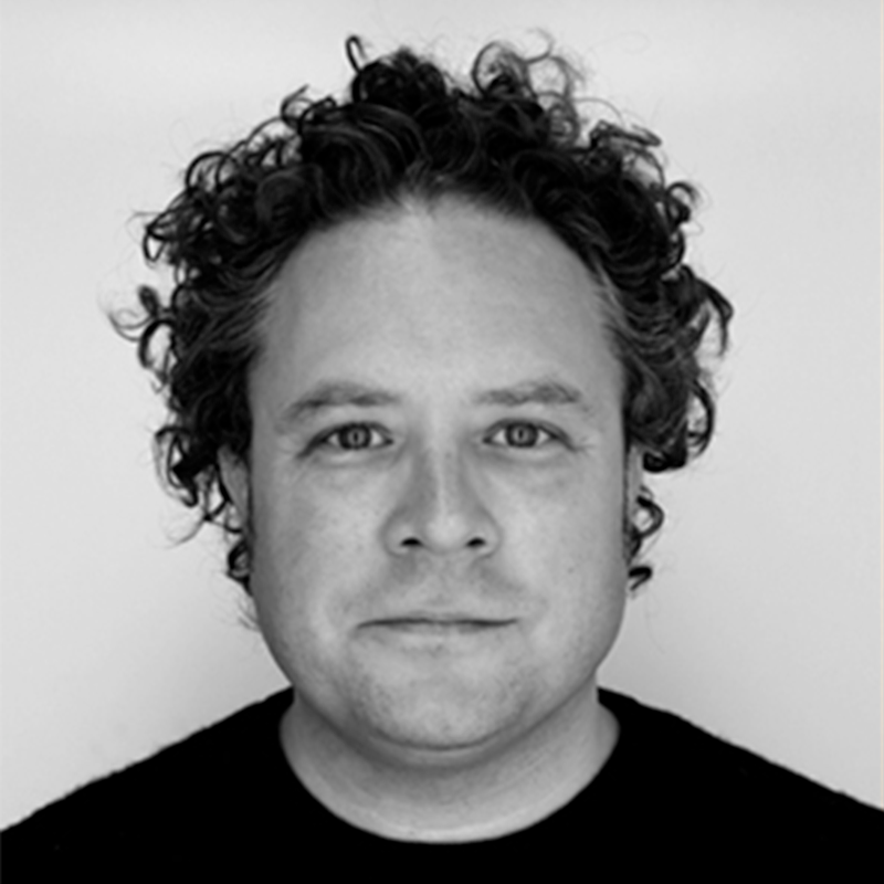 man with curly hair and glasses against a whit background
