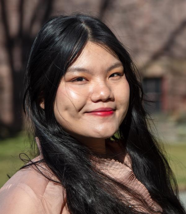 a young woman with long black hair and red lips wearing a pink winter jacket