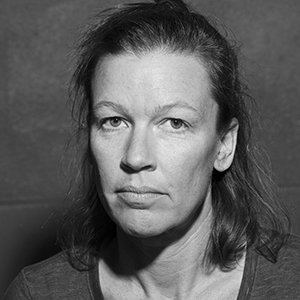 A black and white photo of a person with a light complexion and shoulder-length dark hair.