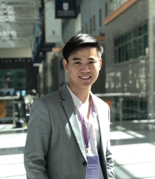 a young man wearing a gray suit jacket and white shirt with a purple lanyard