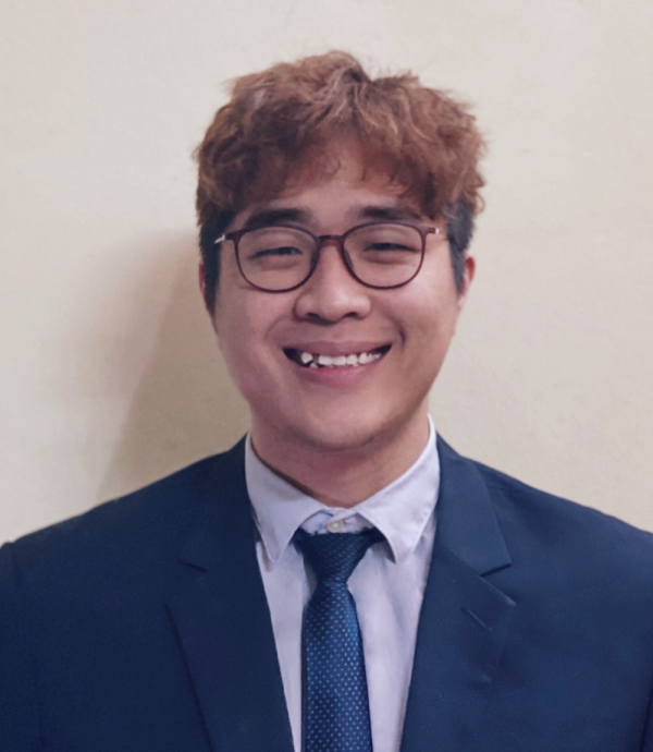 a person smiling with glasses and a blue suit and tie