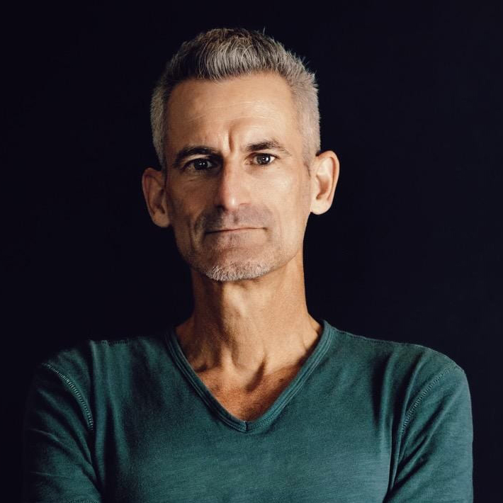 A white male with a green v neck and short grey hair.