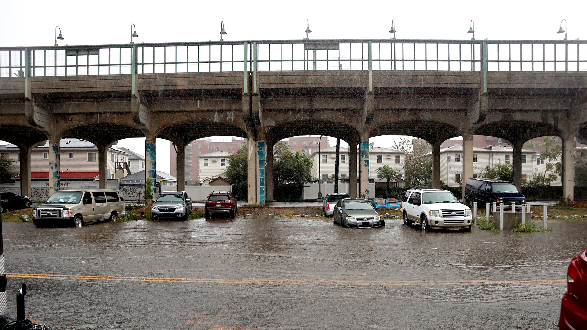 Cars parked outside on along a flooded roadway.
