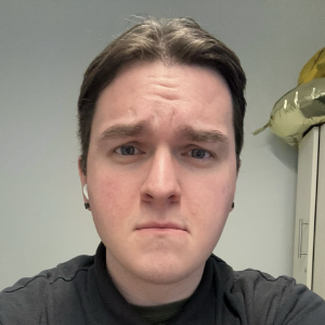 a person with short brown hair. They are not smiling at the camera. They are wearing a gray shirt.