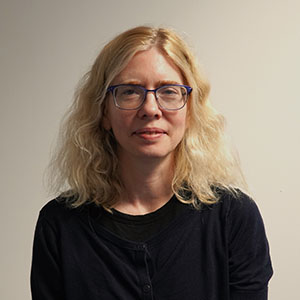 Woman with blond hair and glasses in a black cardigan