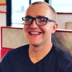 smiling man with black shirt and rimmed glasses