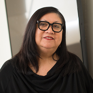 A woman with straight dark hair and black square glasses