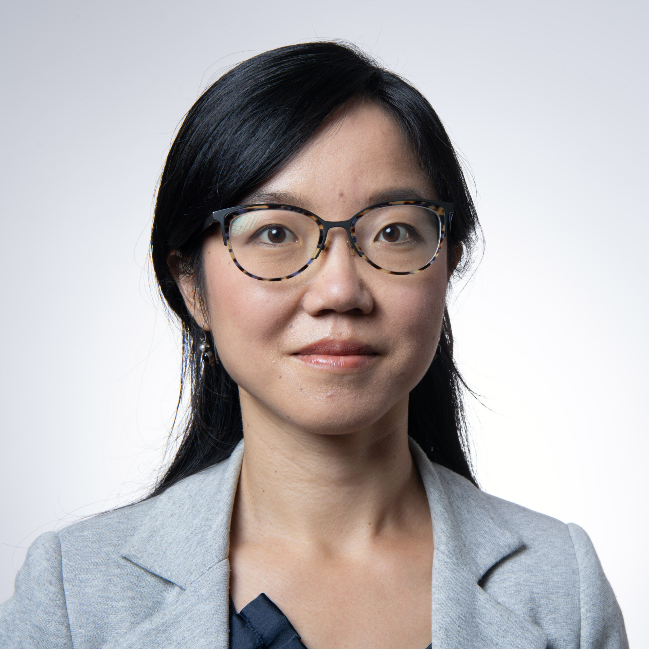 Asian woman wearing glasses and grey jacket