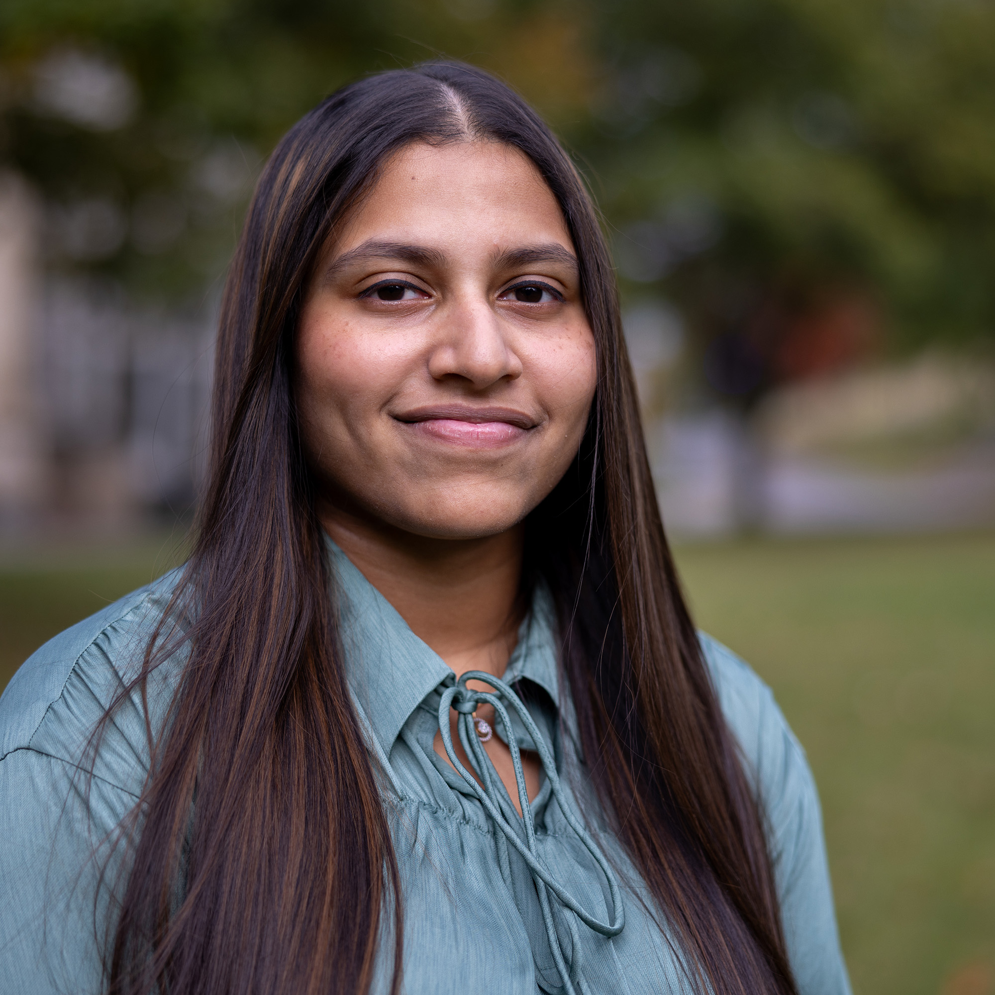 A person with long dark hair wearing a blue shirt.