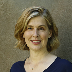 headshot of a woman with blond hair wearing a dark blue shirt