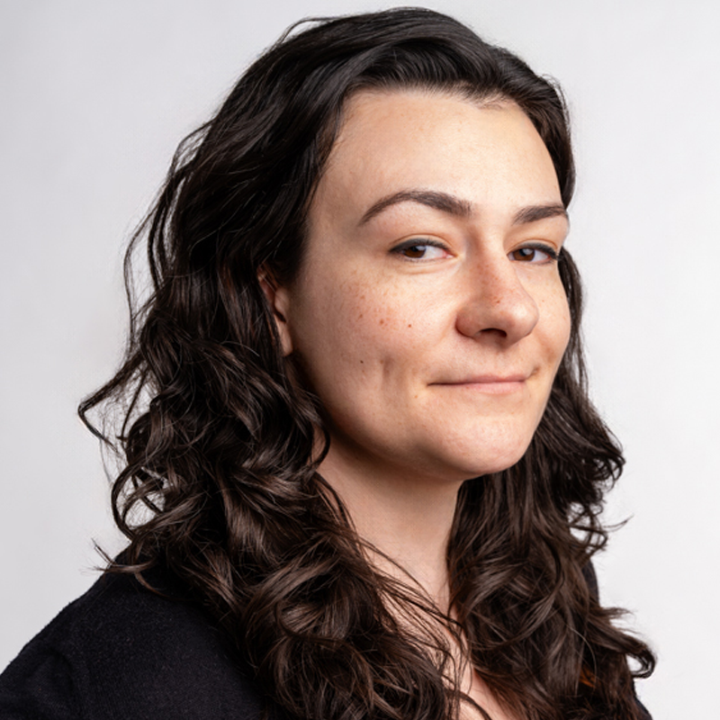 Person with long brown hair staring at camera with white background.