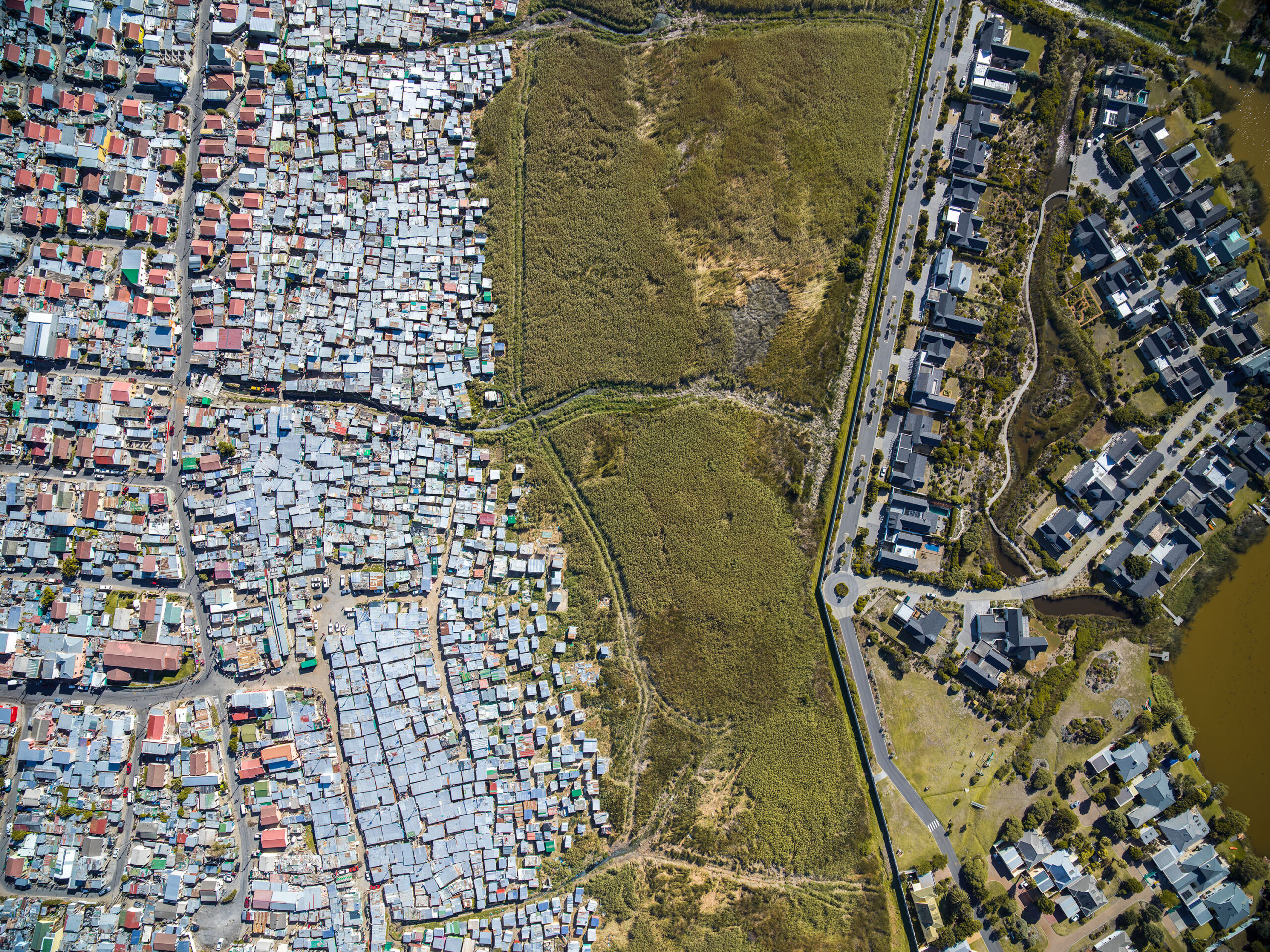 An aerial view of buildings and dwellings across from each other separated by green grass.