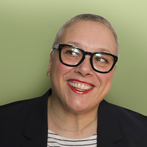 A person with short gray hair wering a pair of glasses and a red lipstick