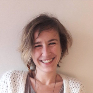 A woman with short blonde hair and a white sweater.