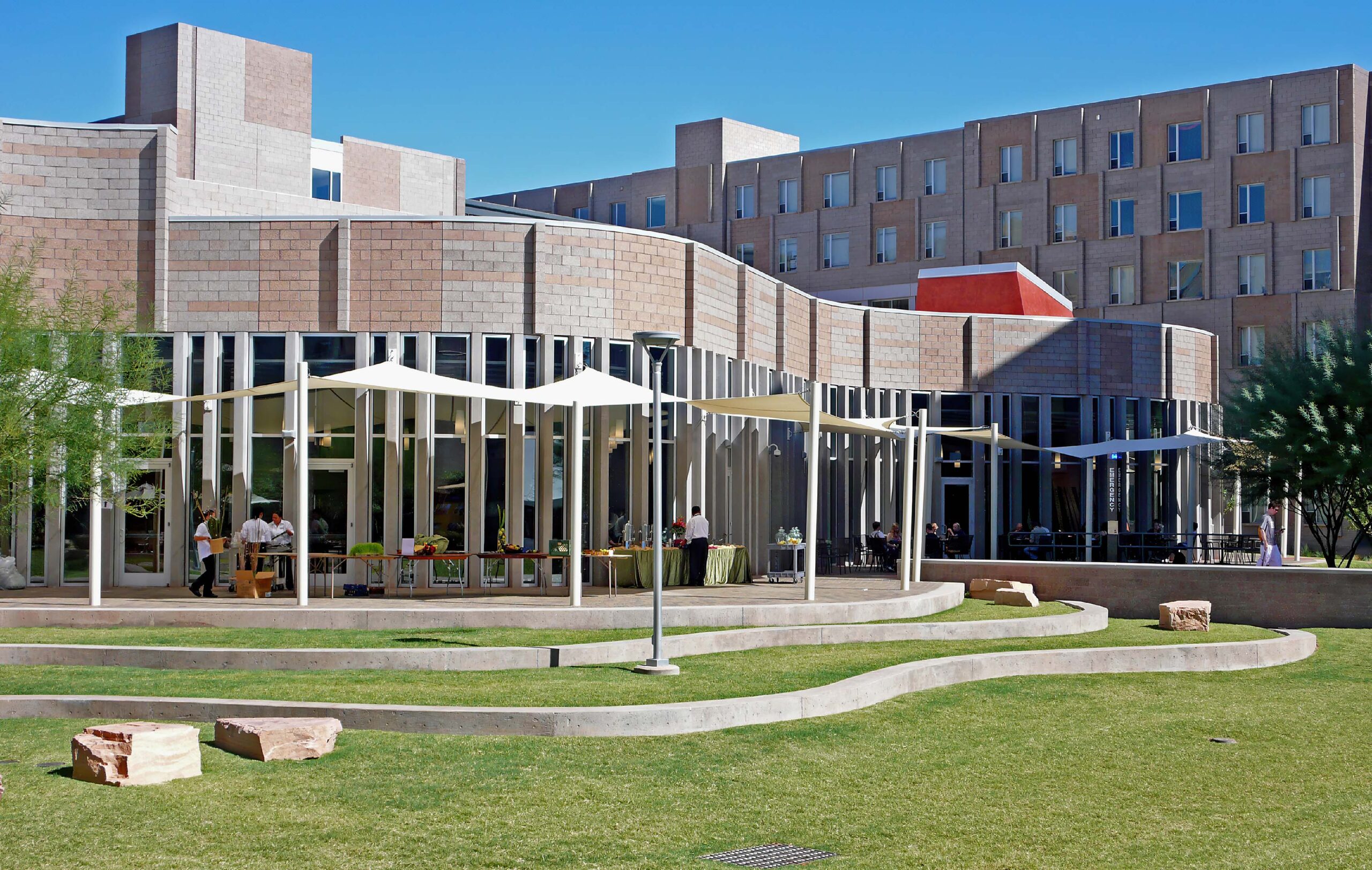 A curving building facade overlooks an exterior dining area.