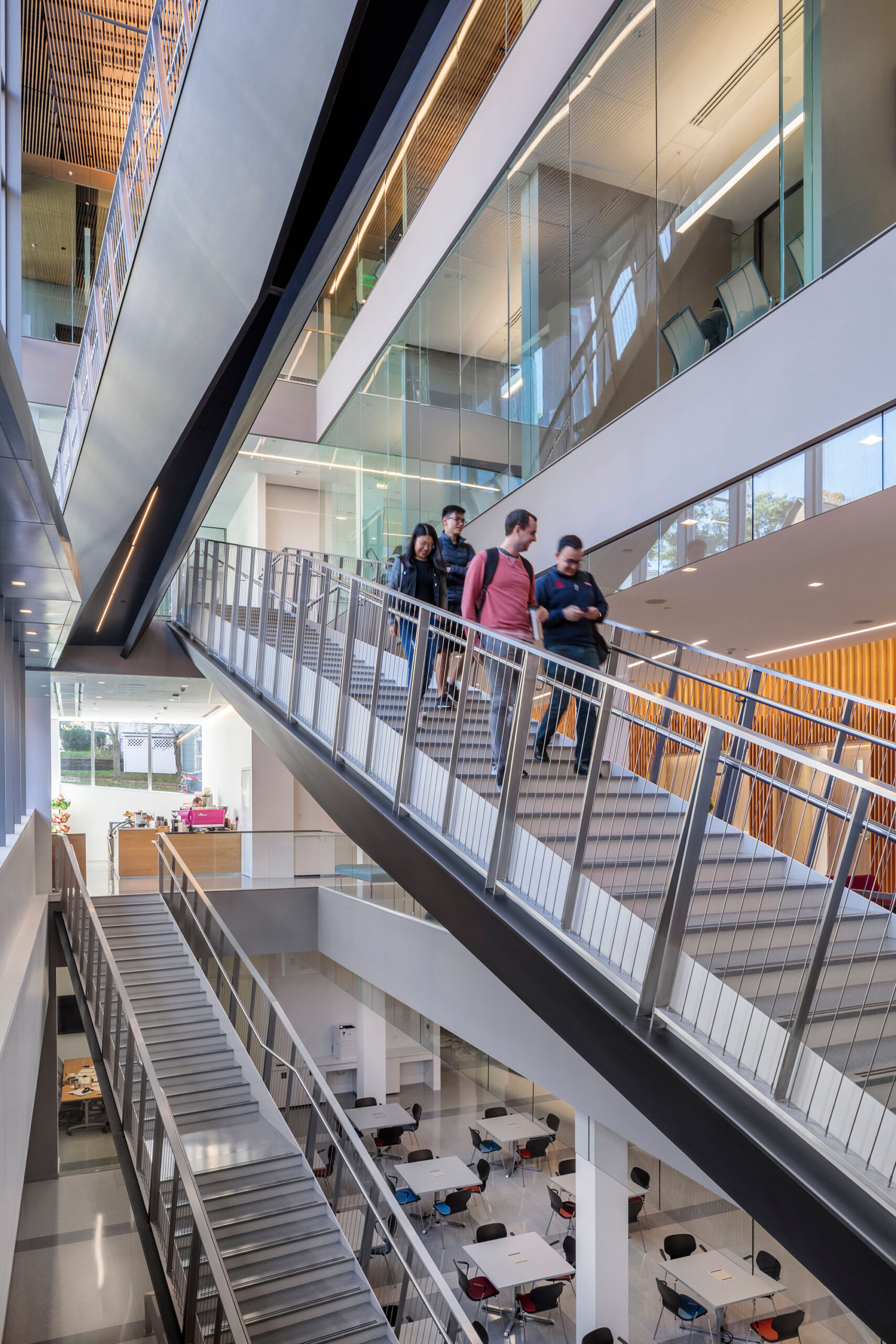 People walk down a staircase in a multifloored building.