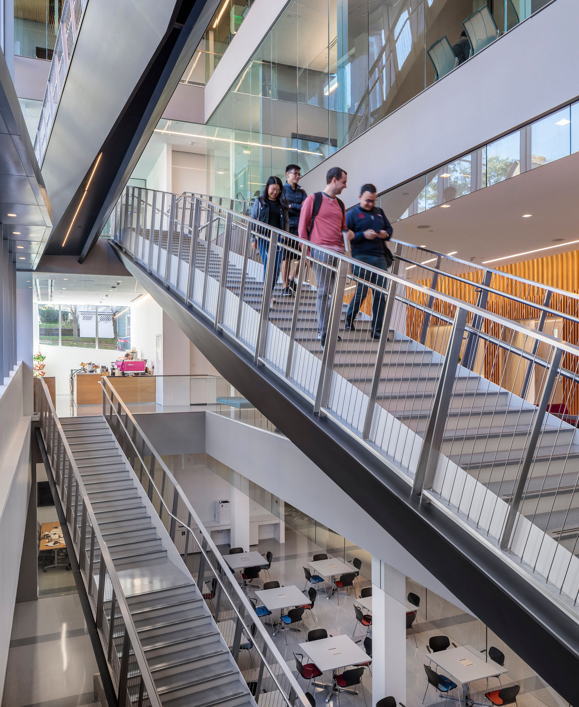 People walk down a staircase in a multifloored building.