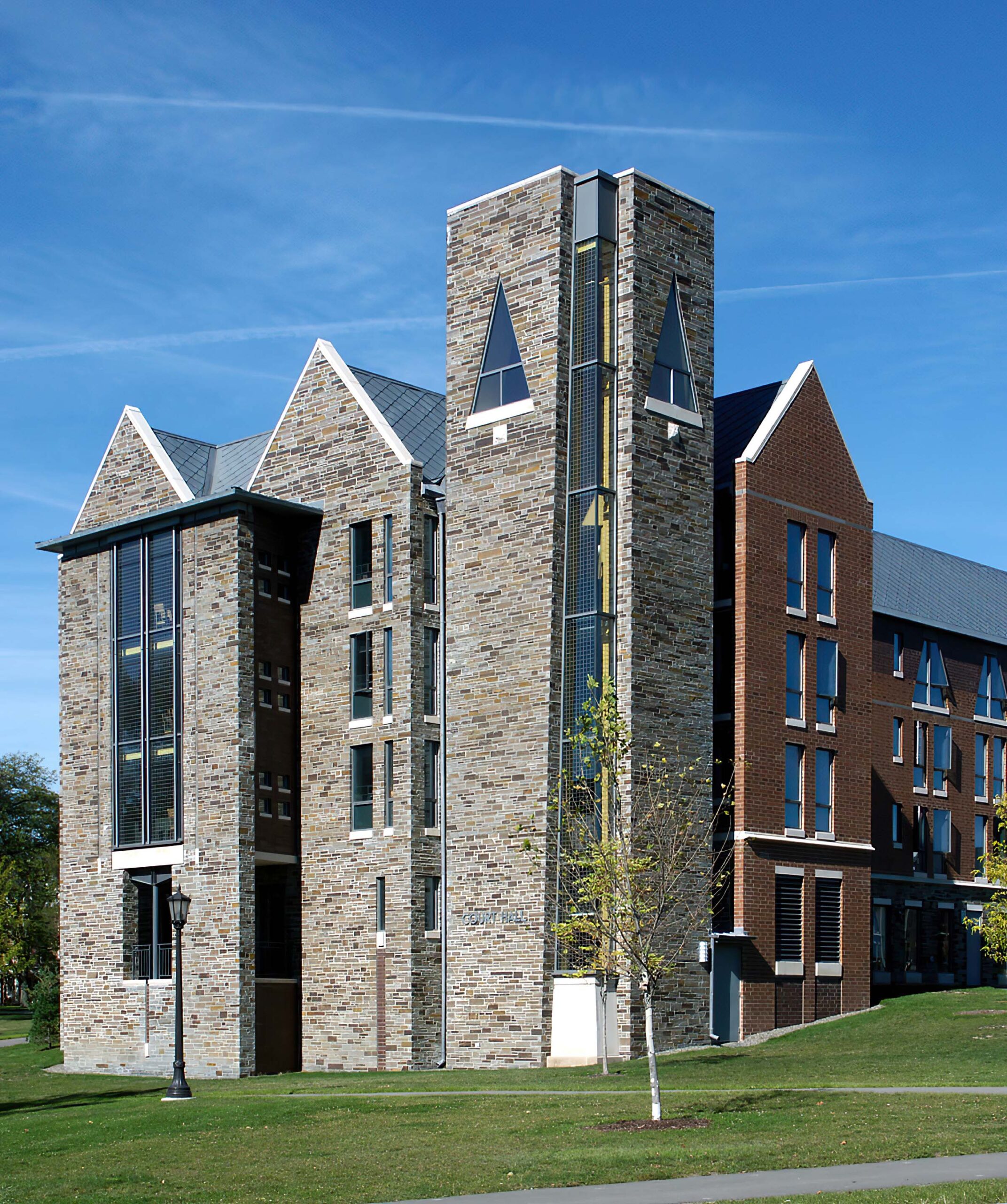 Exterior view of a building with a stone-colored front brick facade and a traditional red brick side facade.