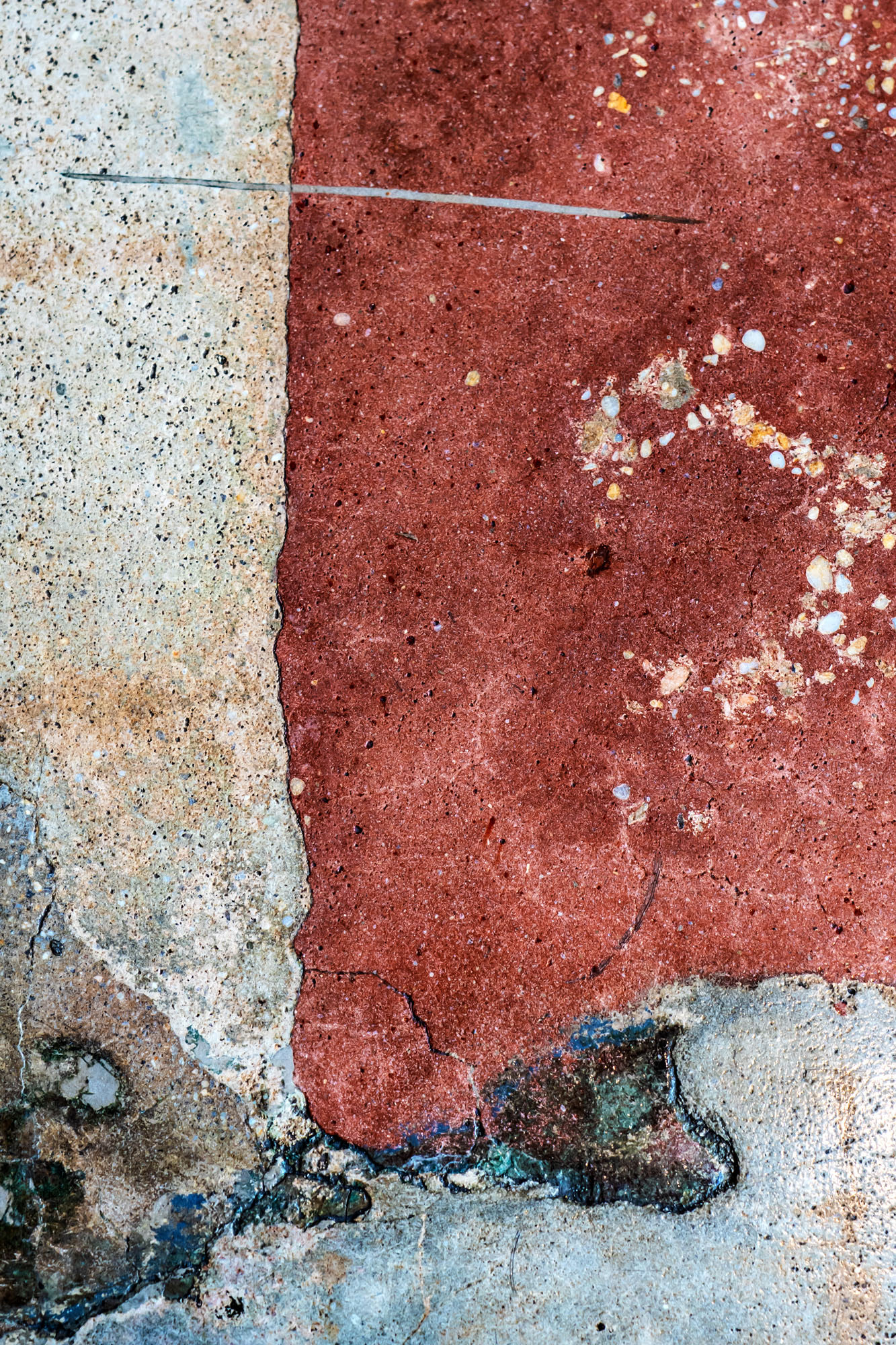 A concrete floor with light-colored, red, and brown sections.