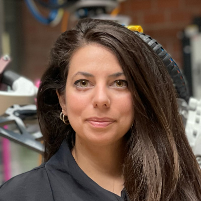 A woman with long dark hair and a grey shirt smiliing.