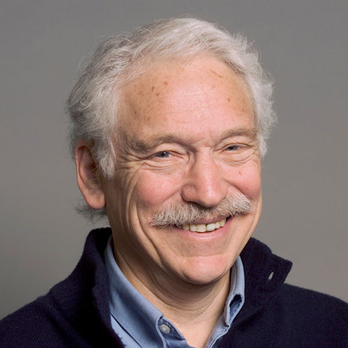 headshot of a man with white hair and a mustache