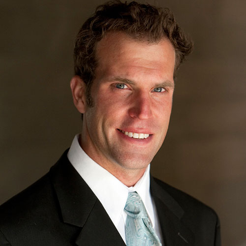 headshot of a man with brown hair wearing a dark jacket