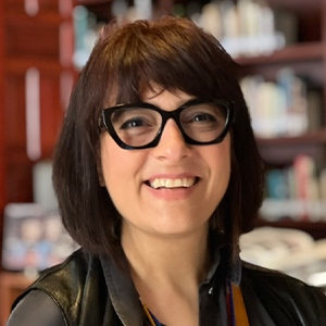 A smillling woman with dark rimmed glasses and medium length short brown hair.