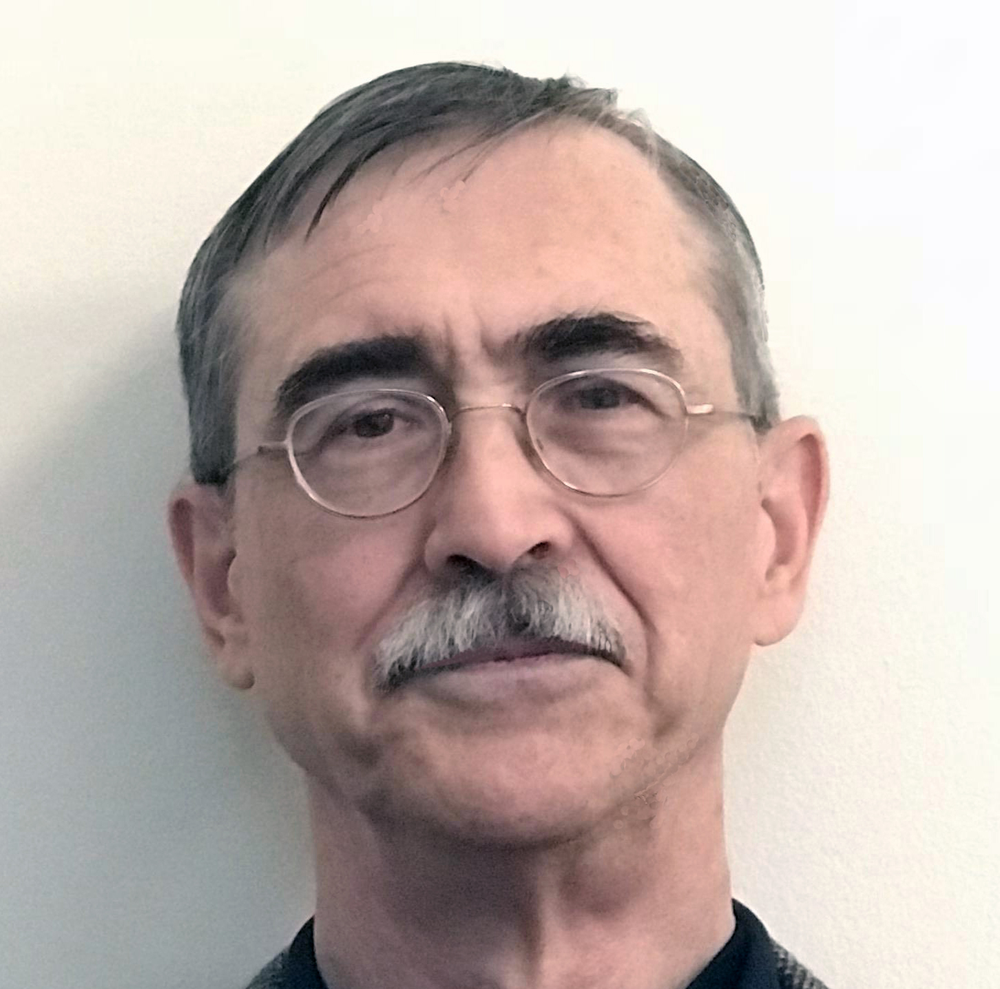 a man with dark hair and a mustache wearing glasses
