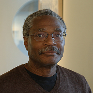 headshot of a man with in glasses with grey hair and a mustache