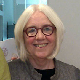 headshot of a woman with light blond hair and red glasses