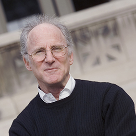 headshot of a man with glasses wearing a dark blue sweater