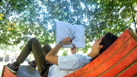 Student reclining under a tree and sketching
