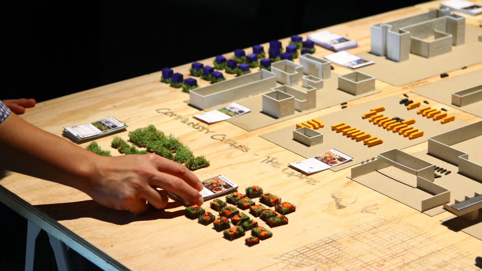 A hand touching miniature pieces of a table top card game.