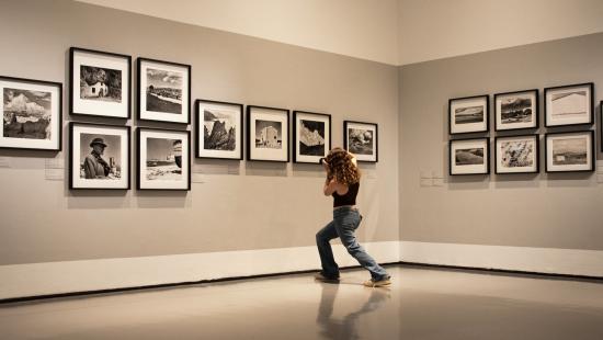 Student photographing a gallery exhibition of black and white images