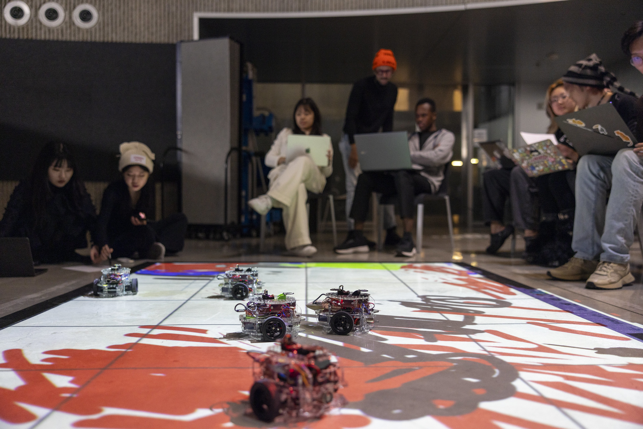 Students gathered around small robots on the floor