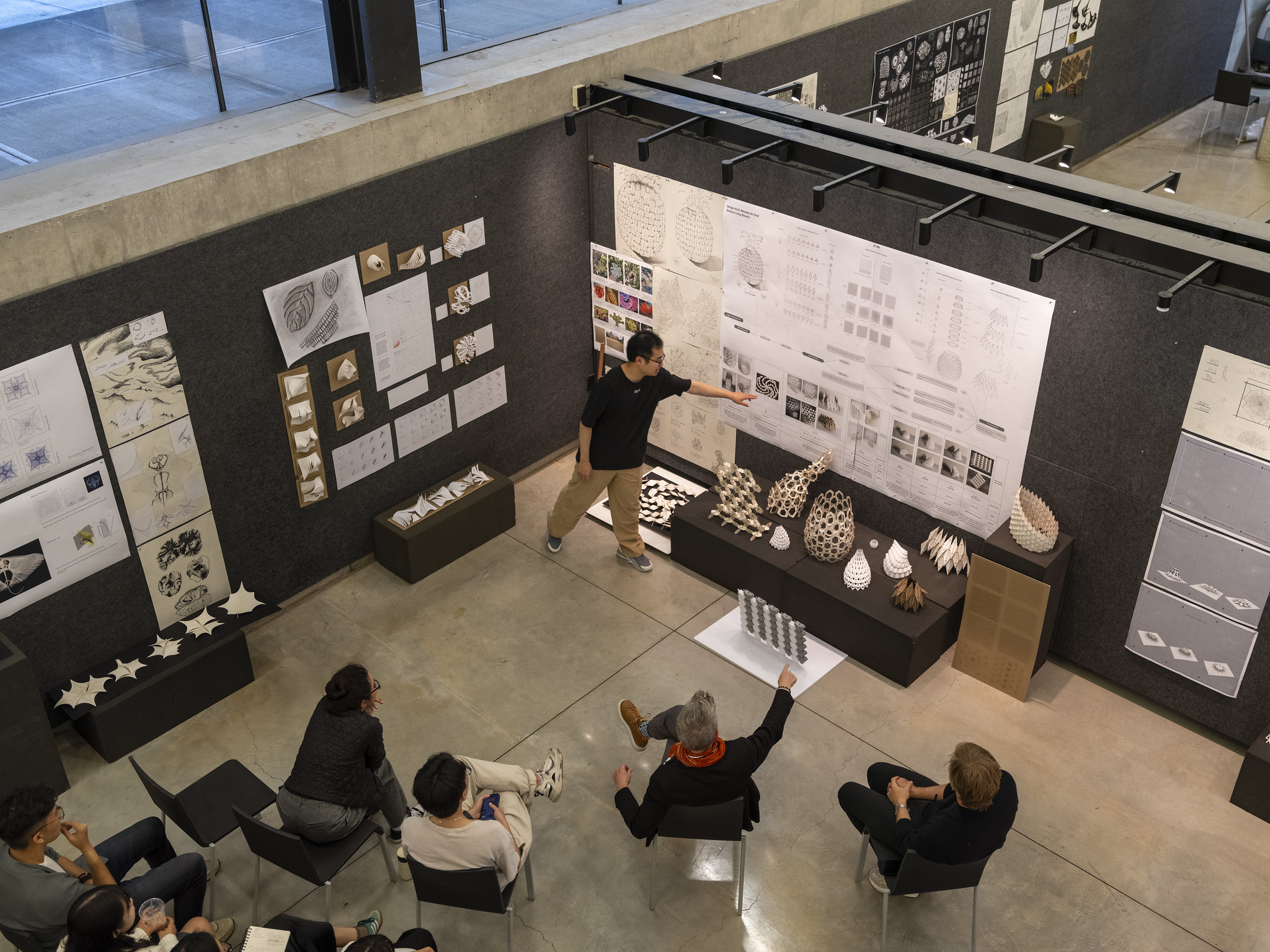 Student presenting pinned up work to a panel