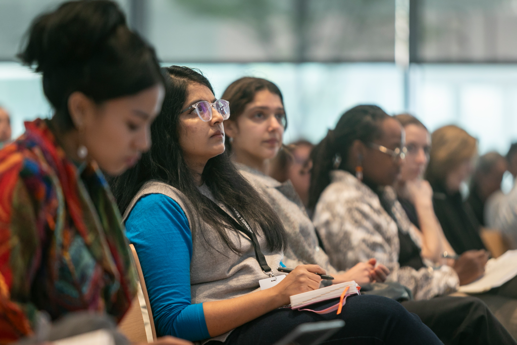 Members of the audience listen and take notes.