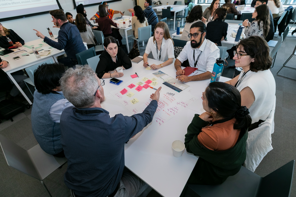 people gathered around small tables work in groups and discuss ideas