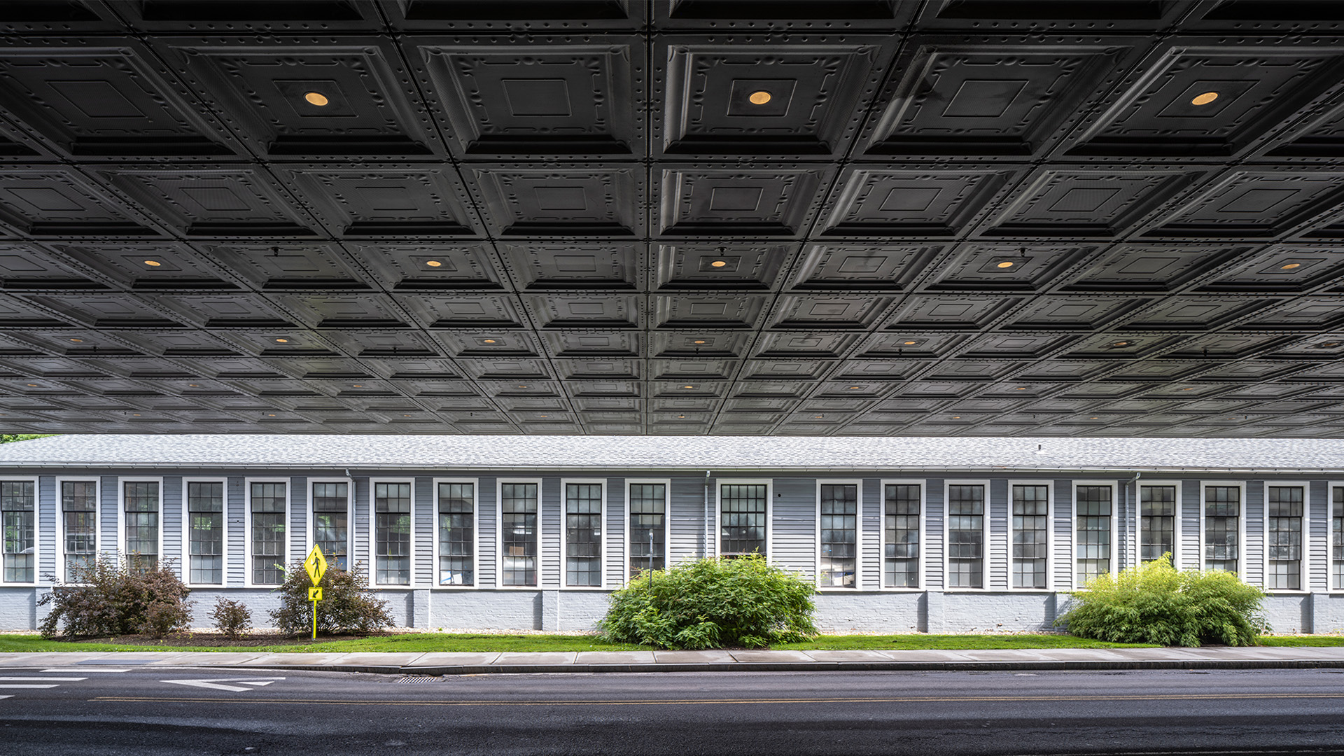 a large grey building with bushes in front of it