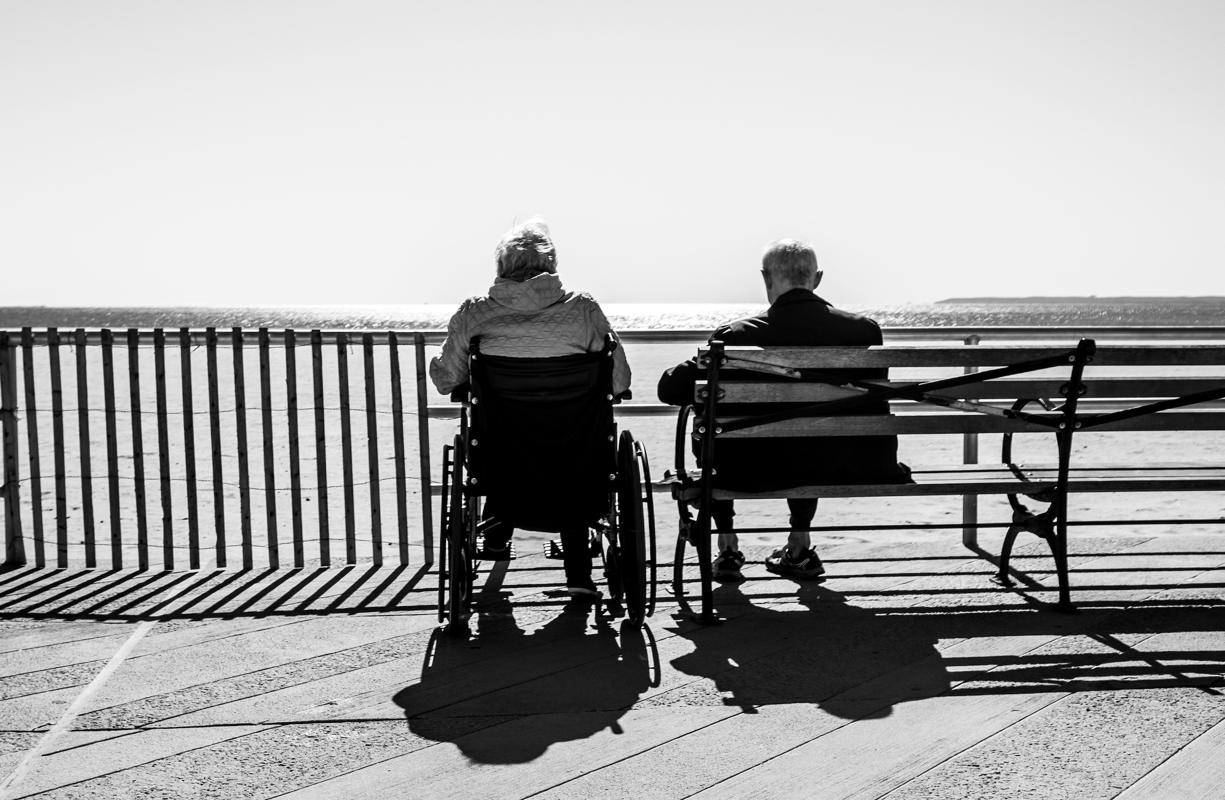 An elderly man and women sit neat the water side.