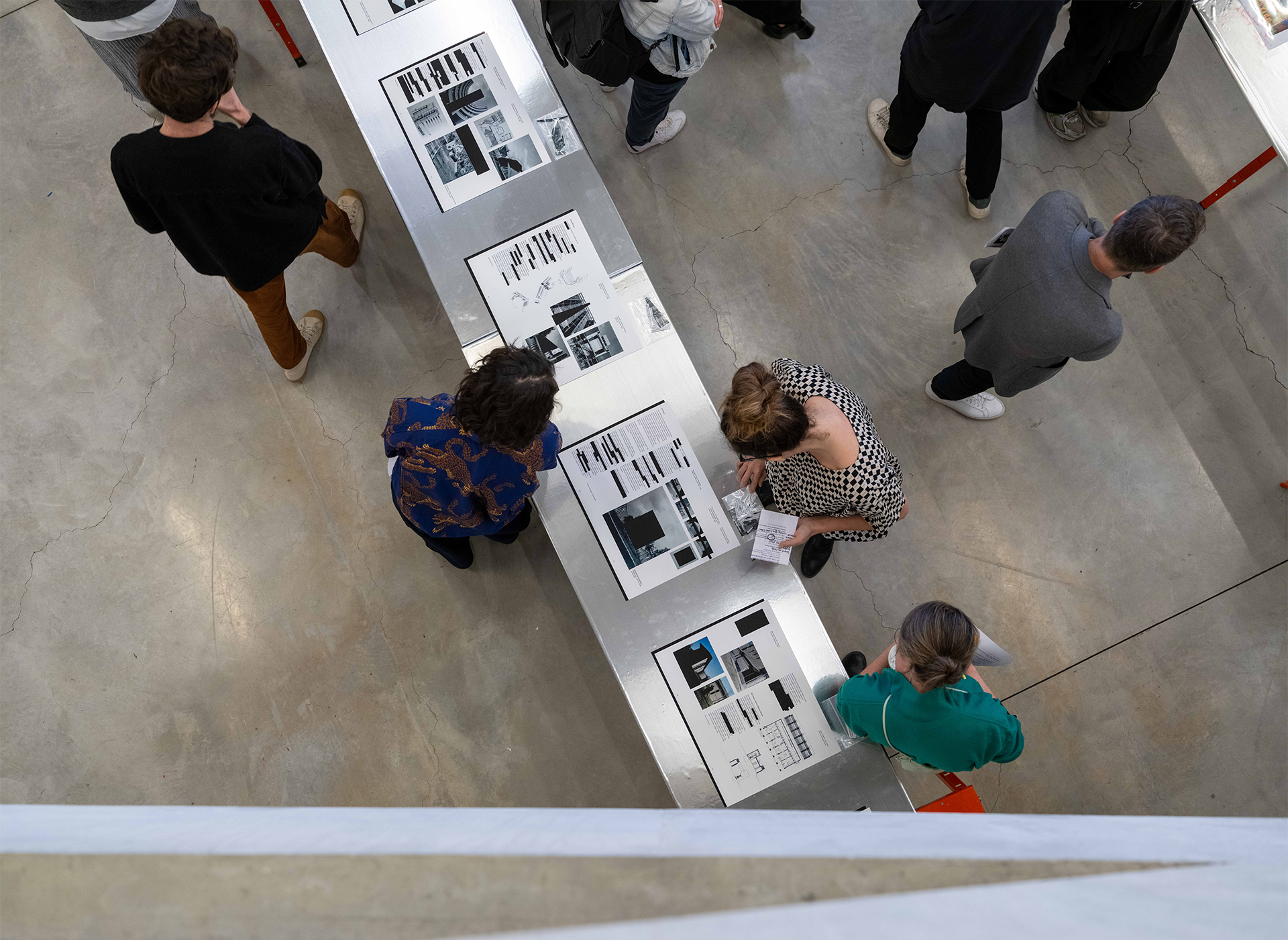 People examining posters laid out on a table